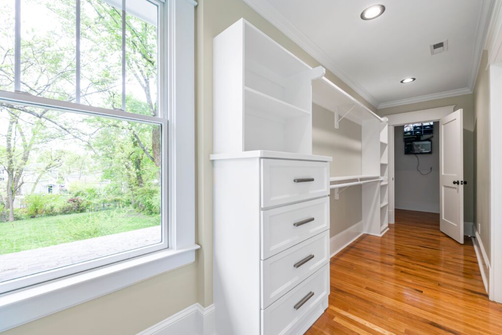 Bright walk-in closet with a closet organizer with drawers, shelving, and hanging rods